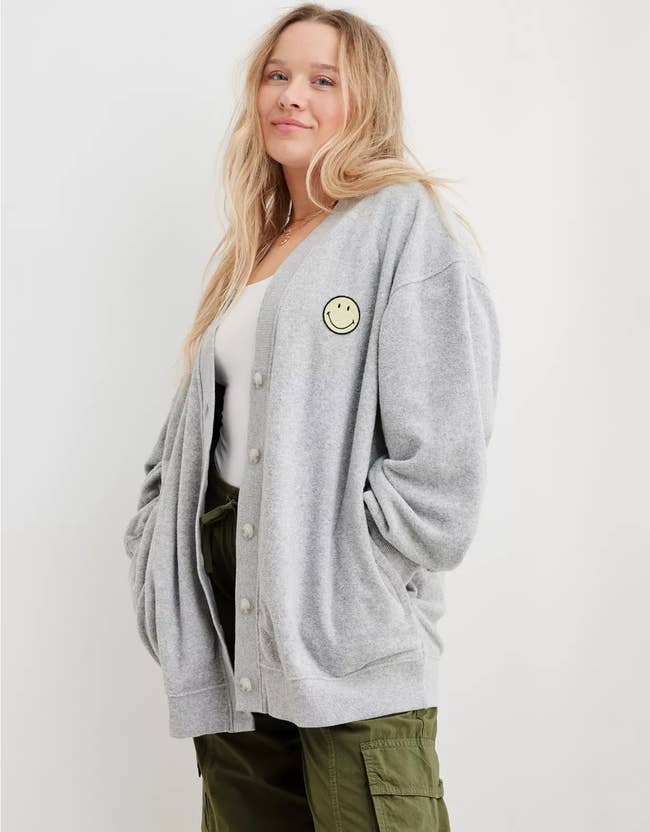 model in long gray cardigan with smiley face patch