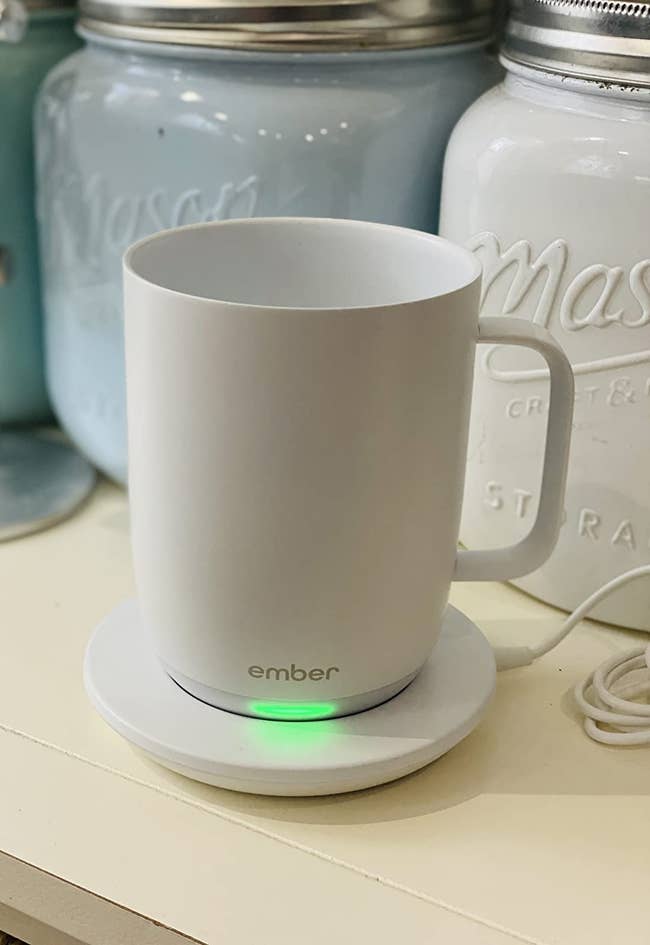 reviewer image of the white ember mug charging on its coaster