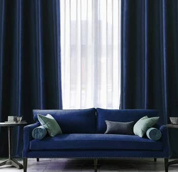 two navy blue velvet curtains hung behind a couch