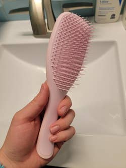 A reviewer holding a pink hairbrush