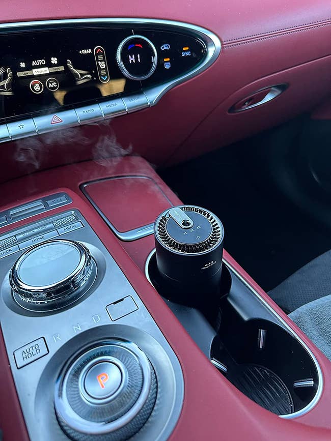 A reviewer's car with the diffuser in the cup holder and steam coming out of it