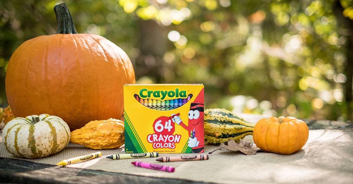 pack of 64 crayons next to pumpkins