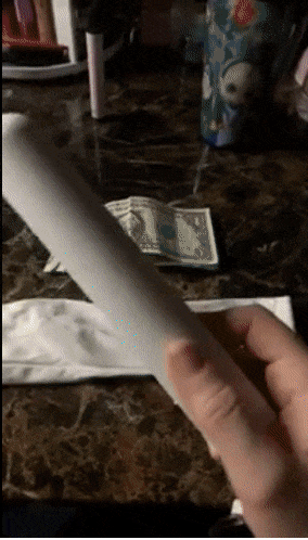 A reviewer using the wand to sanitize dollar bills 