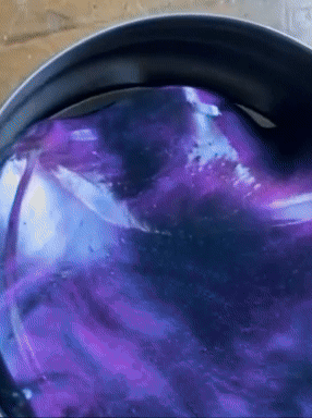 Shimmering purple putty is stirred successful  a container, showcasing a mesmerizing, glossy finish