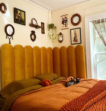 Cozy chamber  with a ample  mustard-colored headboard, brownish  bedding, and partition  art. A feline  lounges connected  the bed. Various decorative mirrors and plants adorn the walls