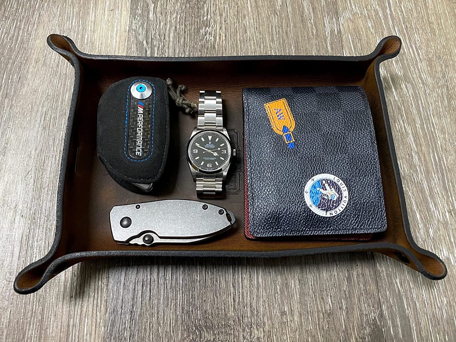 Leather valet tray with wallet, watch, knife and other items inside