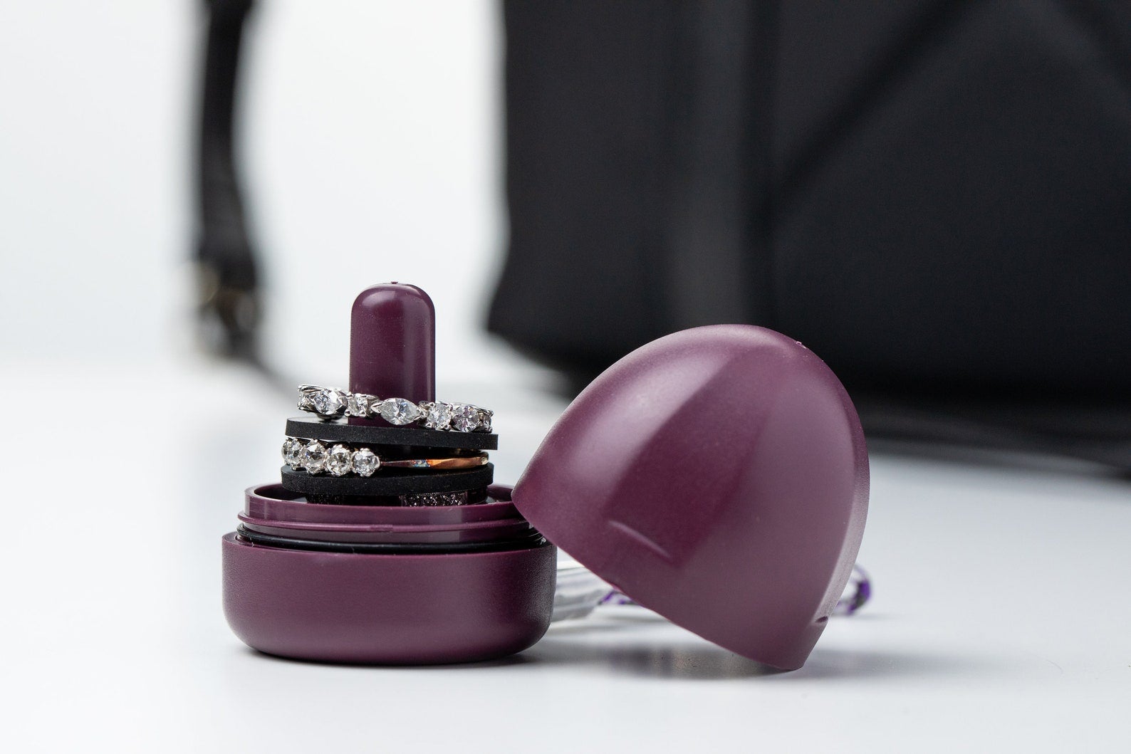 A small purple dome-shaped storage piece with a cylinder holding several rings and a lid to twist on top of it