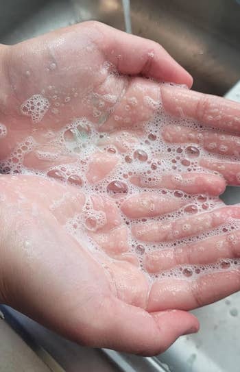 Hands cupped unneurotic  with soap lather, held nether  moving  water, highlighting handwashing technique