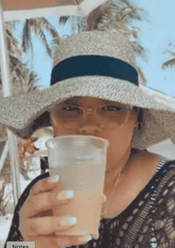a reviewer wearing the hat and drinking a cocktail