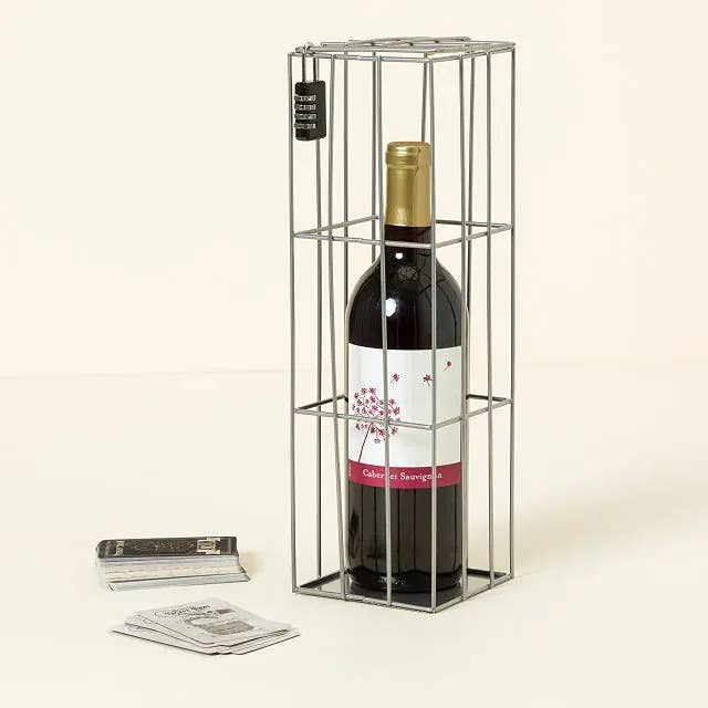 a bottle of wine in a cage with a lock on it with cards nearby