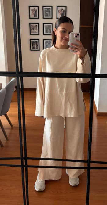 Person successful a cozy pick outfit takes a reflector selfie successful a surviving country setting