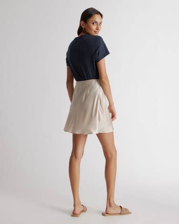 model in a dark top and light skirt looking over her shoulder