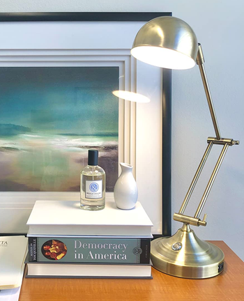 reviewer photo of a gold task lamp shining on a desk