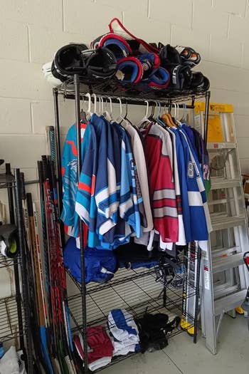 Sports gear on a rack with jerseys, helmets, and equipment for various sports