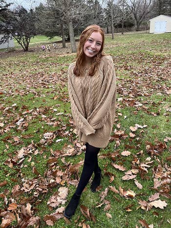 reviewer photo wearing the sweater dress in brown, amongst leaves