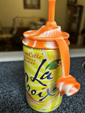 LaCroix LimonCello sparkling h2o  tin  with an orangish  silicone straw topper shaped similar  a twisty straw handle