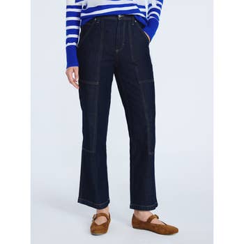 Person wearing dark denim wide-leg jeans with visible stitching and brown shoes, paired with a striped top