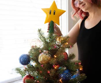 model putting star on top of tree