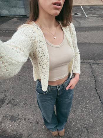 Person successful knitted cardigan, vessel top, and jeans, lasting outdoors connected pavement