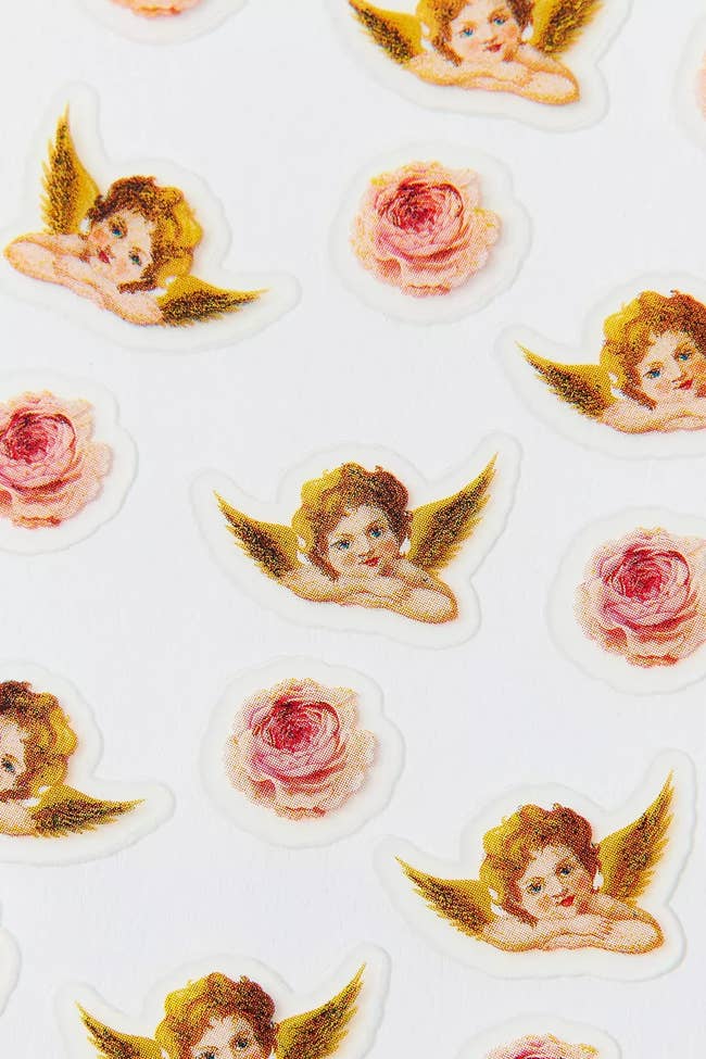 Stickers of cherubs with aureate  wings and pinkish  roses scattered connected  a achromatic  background