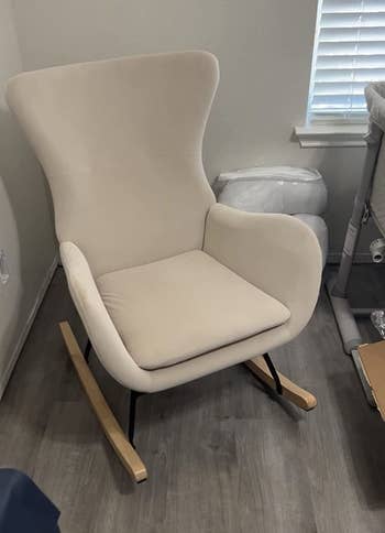 Reviewer image of side view of product in velvet white with black legs connecting the wooden rocker legs