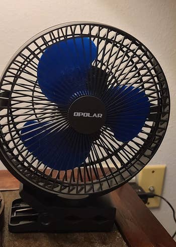 Reviewer image of black battery powered fan on top of wooden desk