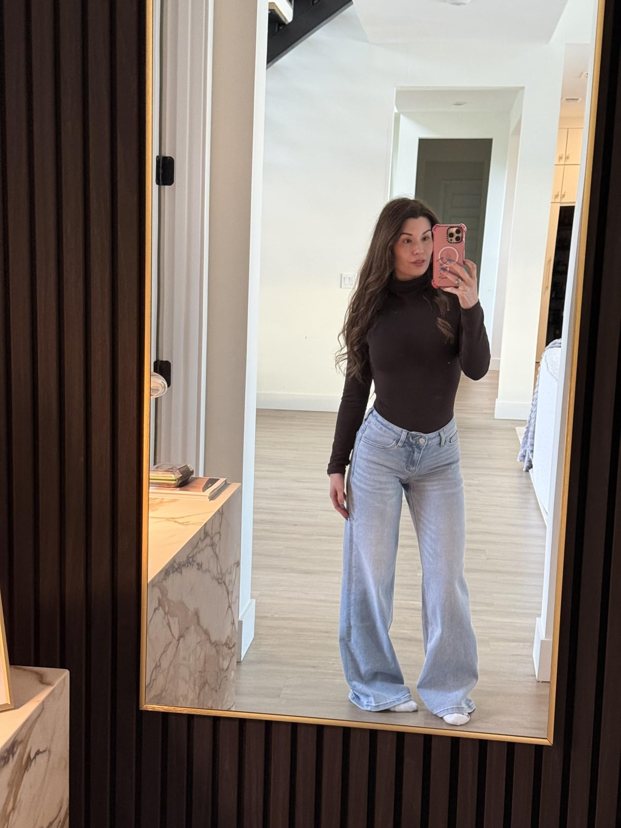 Person taking a reflector  selfie wearing a fitted apical  and wide-leg jeans, lasting  successful  a modern   interior space
