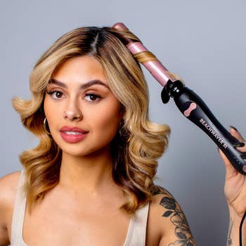 Woman using a curling wand on her shoulder-length hair