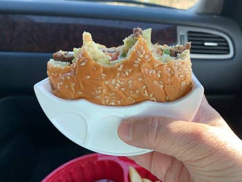 reviewer showing a burger holder as they eat a burger in their car