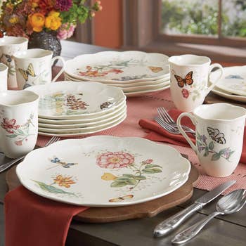 the dinnerware set with floral and butterfly designs displayed on a table