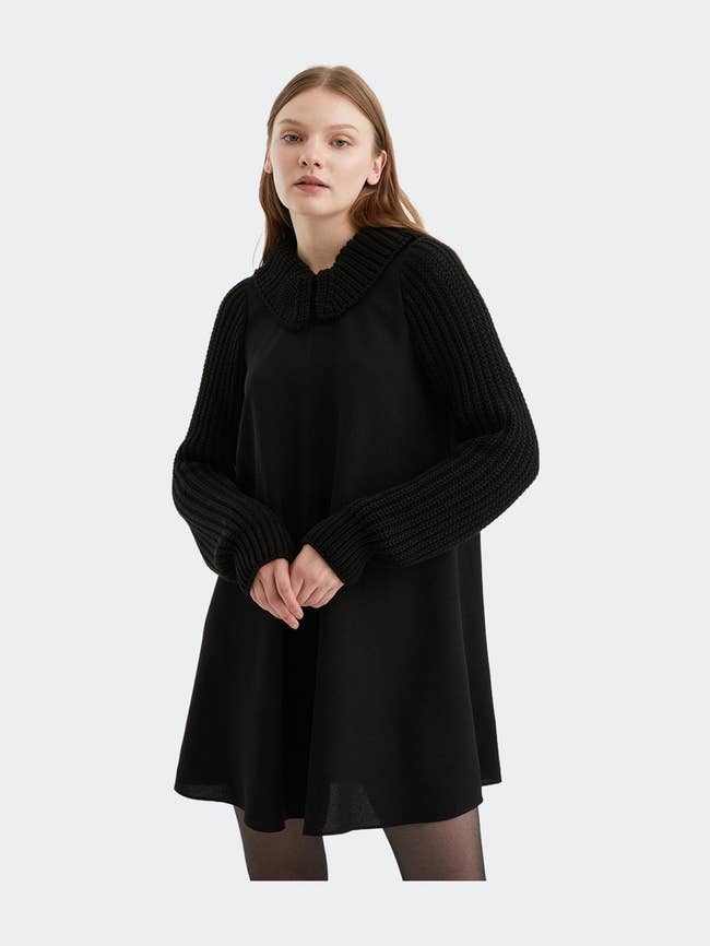 a model in an above the knee black knit dress with a black peter pan collar
