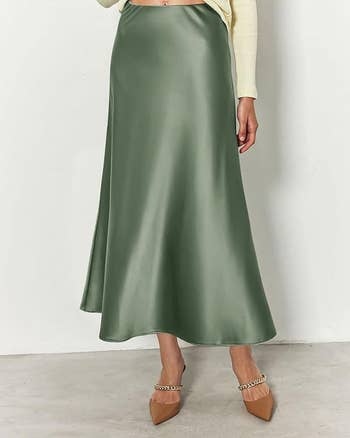 Person wearing a green satin maxi skirt with chain embellished beige heels