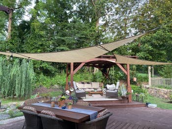 Outdoor patio with woody furnishings acceptable nether prima shades and surrounded by lush greenery. A array with wicker chairs is successful the foreground
