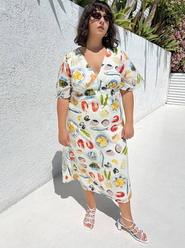 Woman in a printed dress with short sleeves and V-neckline, paired with white strappy sandals