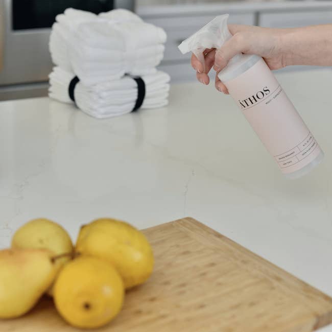 A model spraying the orange scent on kitchen countertops