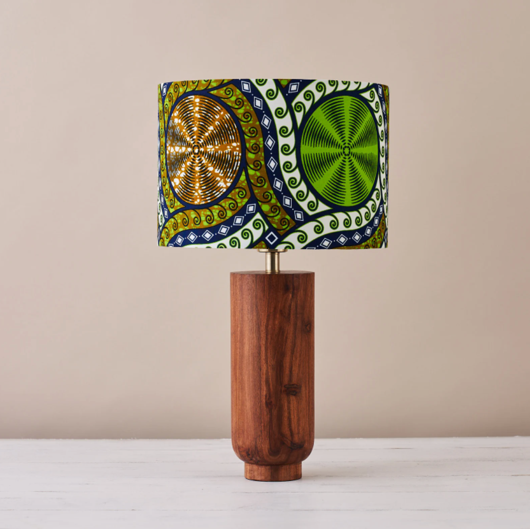 Green, blue, white, and brown geometric-patterned lampshade with wooden bottom on a white table