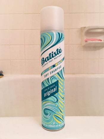 评论家干燥的蓝瓶洗发水的照片站在浴缸的边缘”class=