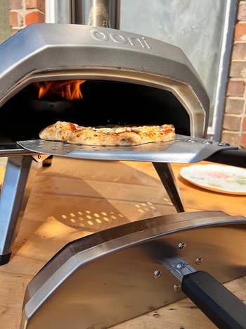 reviewer using pizza oven to make pizza