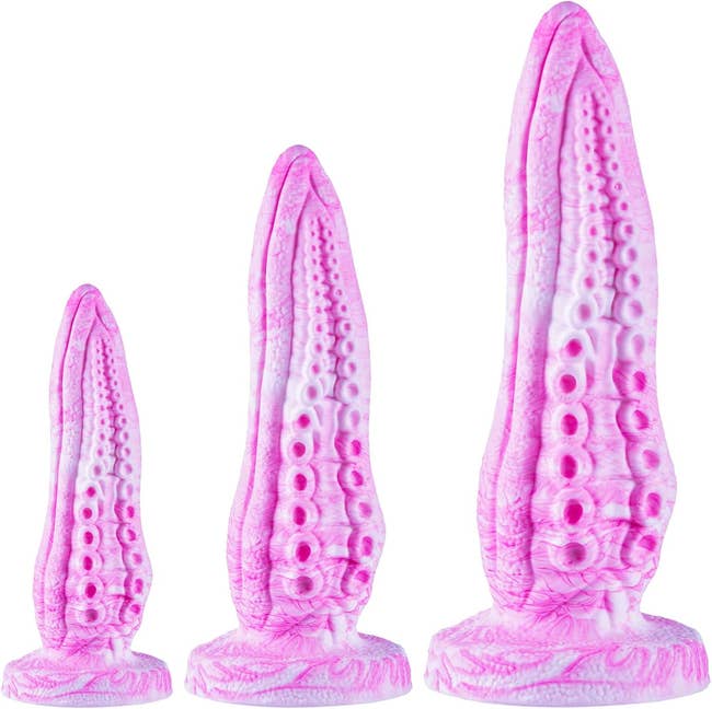 Three pink, tentacle-shaped textured silicone toys successful varying sizes displayed upright connected bases