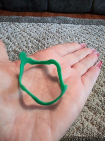 Reviewer holding a green bracelet toy in their palm