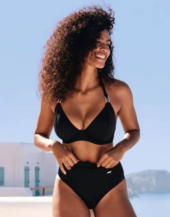 a model wearing the plunge top in black with a pair of matching bottoms
