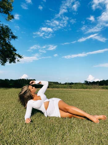 reviewer laying in grass posing while wearing white two piece outfit