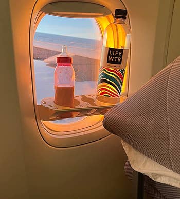 reviewer photo of the bevledge attached to a plane window holding an infant's bottle and water bottle