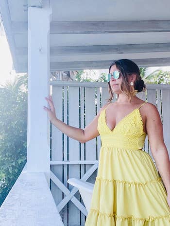 reviewer in yellow v-neck high waist cinched dress with tiered mid length skirt 