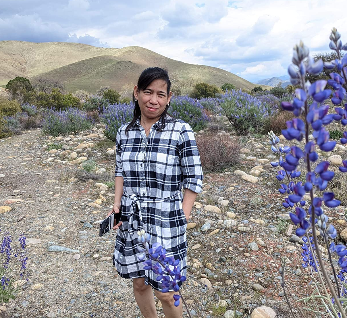 reviewer photo wearing the dress in white and black plaid posing on trail