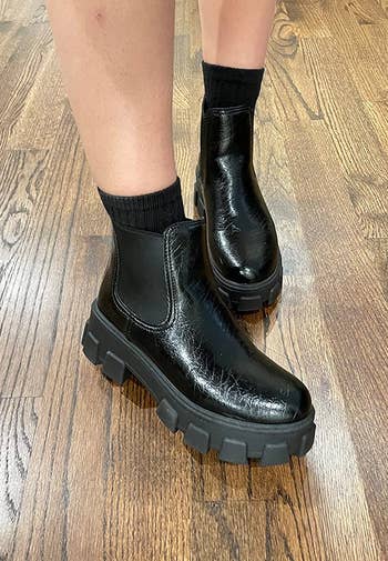 reviewer wearing the chunky black boots in the glossy crinkle style