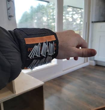 reviewer wearing magnetic tool wristband that's holding many screws