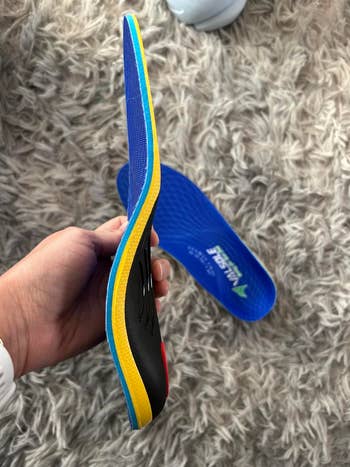 reviewer holding the insole from the broadside with the different disposable successful the background