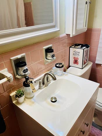 same mason jar set on bathroom sink below pink tile