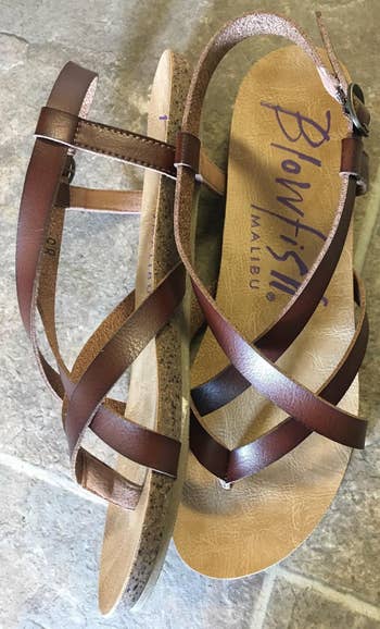 A reviewer's pair of brown leather strappy sandals with the brand name 'Blowfish Malibu' on the insole